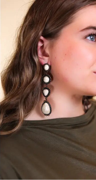 Close-up of a woman wearing a pair of earrings with a neutral background