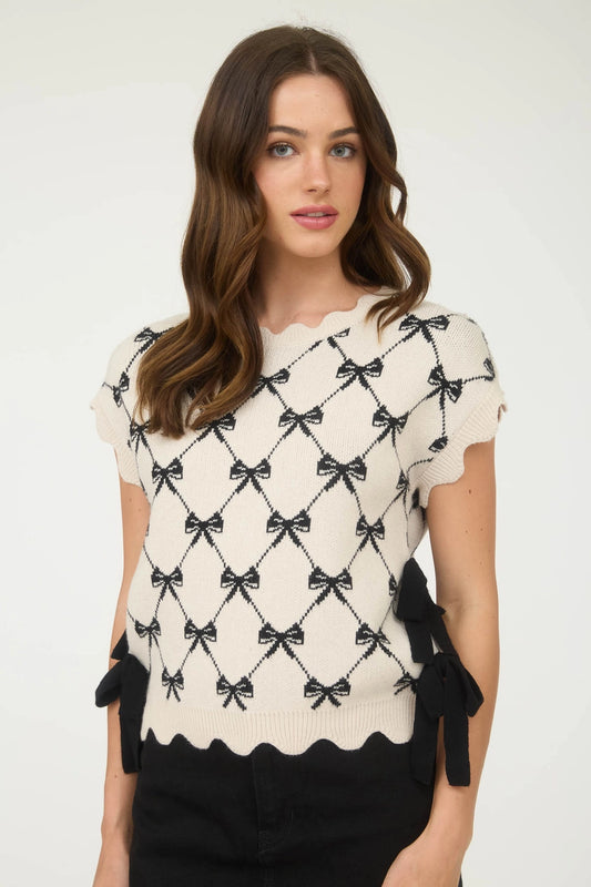 White scallop sweater with black bow pattern.