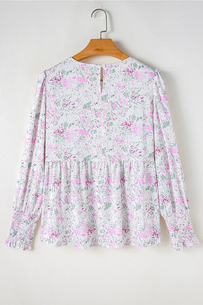 Floral Print Blouse. This blouse features a charming floral print in soft, pastel tones. The design includes a flattering V-neckline, long puffed sleeves with smocked cuffs, and a relaxed, flowy fit.
